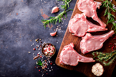 Meat Raw Fresh Mutton on the bone Spices Chesno and Rosemary on a black background Top View Copy space for Text Meat Raw Fresh Mutton on the bone Spices Chesno and Rosemary on a black background Top View Copy space for Text
