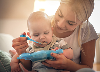 Happy mother with baby boy at home giving baby food. Close up. Happy mother with baby boy at home giving baby food. Close up.