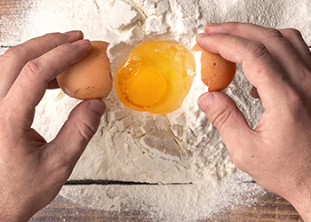 Male hands beat the egg yolk into the flour Male hands beat the egg yolk into the flour