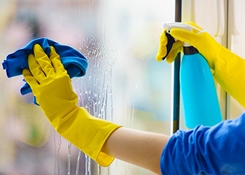 Gloved hand cleaning window rag and spray Gloved hand cleaning window rag and spray