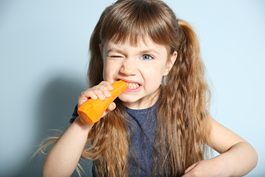 Little girl with carrot on wall background Little girl with carrot on wall background